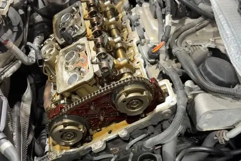 A BMW engine with the valve cover off, showing the camshafts and timing chain