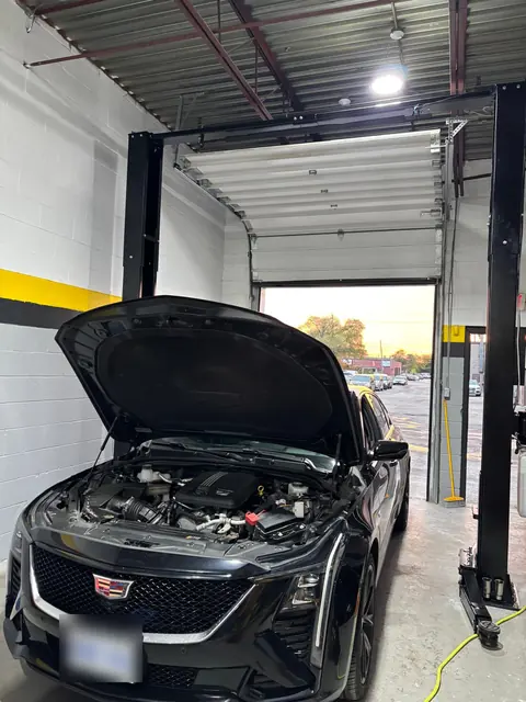 A Cadillac CT5 with the hood open by the bay door