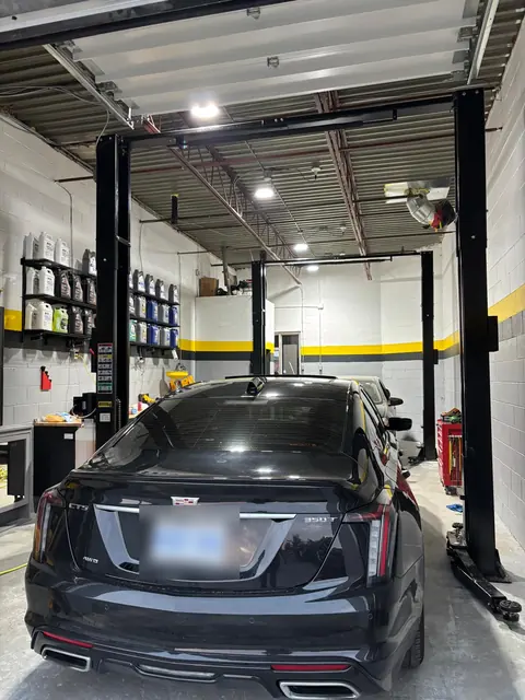 A black Cadillac between the two hoists at GTS Auto Repair