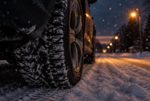 A winter tire on a snow-covered road at dusk